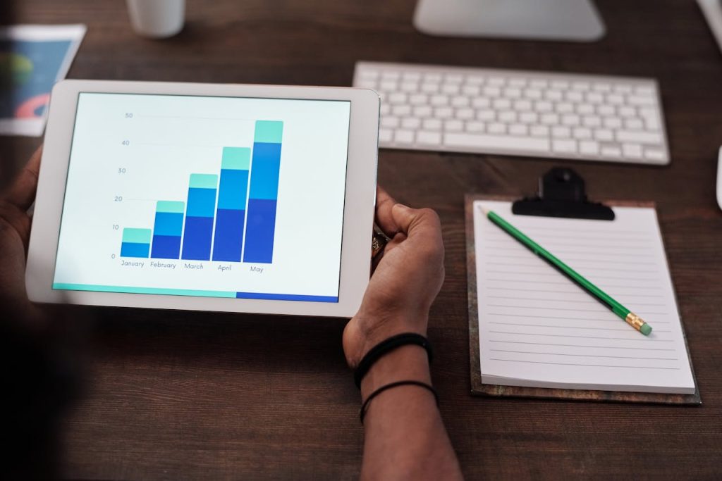 Person am Schreibtisch hält ein Tablet mit Wachstumsdiagrammen unseres Services. Person am Schreibtisch hält ein Tablet mit Wachstumsdiagrammen unseres Services.